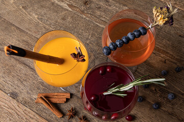 Different cocktails in wine goblets decorated with fresh berries on wooden table 