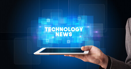 Young business person working on tablet and shows the inscription: TECHNOLOGY NEWS