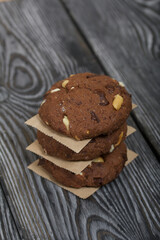 Oatmeal cookies with peanuts and chocolate. Folded in a column and laid out with paper. On pine boards.