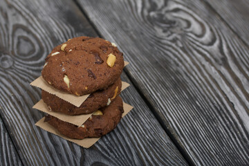 Fototapeta na wymiar Oatmeal cookies with peanuts and chocolate. Folded in a column and laid out with paper. On pine boards.