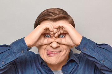 Portrait of funny man making binoculars with hands and looking afar
