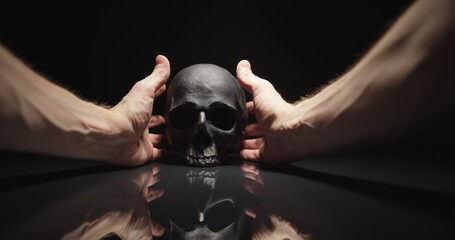 Hands reaching for black skull with reflection