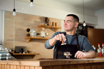 Barista presses ground coffee using tamper in a coffe shop