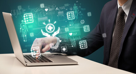 hand browsing on the internet for medical issues with powerful healthcare icons coming out from the screen