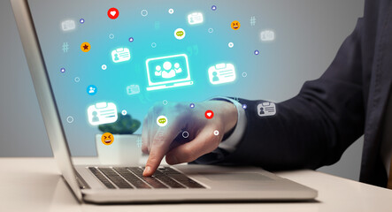 Hand surfing on the social media with laptop icons coming out from the screen, networking concept