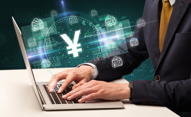 Fototapeta na wymiar business hand working in stock market with yen icons coming out from laptop screen