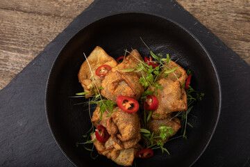 Deep fried, crispy dumplings  in black bowl on black slate
