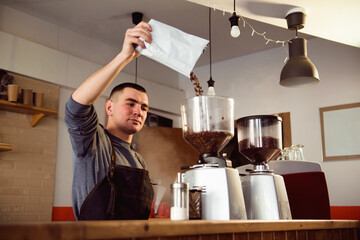 Barista makes espresso in cafe. Barista grind beans with coffee machine. Coffee grinder grinding...