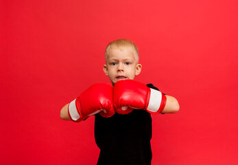 angry boy boxer in red boxing gloves on red background with space for text