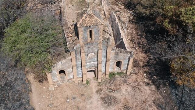 Old dilapidated church on a hill in Tanzania. Brown stone building, Steeple is still standing, Video is zooming away from steeple. The chu was built by White Father by White Fathers in 1800s