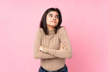 Young woman over isolated pink background making doubts gesture while lifting the shoulders