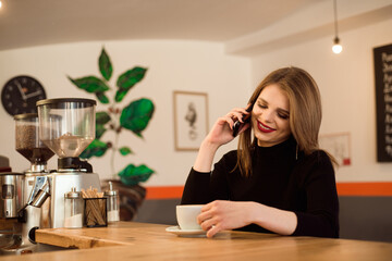 happy Caucasian female watching her photo on cell telephone while relaxing in cafe.