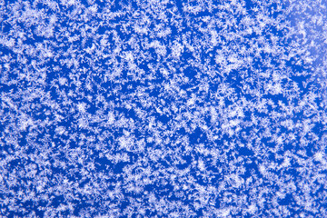 There are white snowflakes on the blue surface. Background, texture of snow. Soft focus