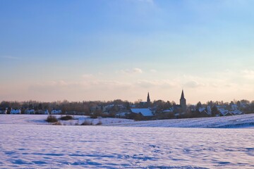 the catholic and protestant church of homberg in winter with snow and blue sky	
