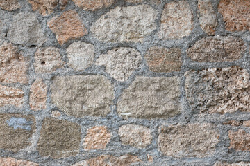 Stone wall made of huge large bricks with concrete and cement. Sturdy building structure in Antalya, Turkey. Textured background with details.