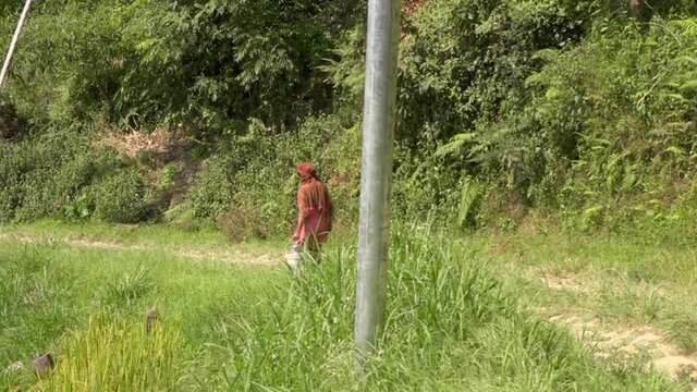 Woman carrying bucket along dirt footpath, Banepa, Bagmati Province, Nepal