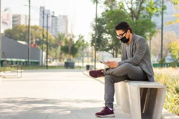A young businessman wearing a face mask while working on a tablet on the street