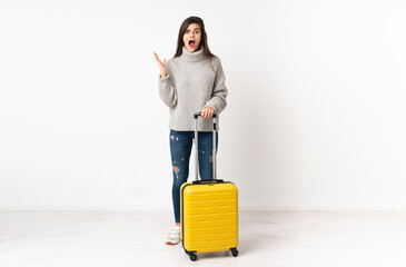 A full length body of a traveler woman with a suitcase over isolated white wall with surprise facial expression