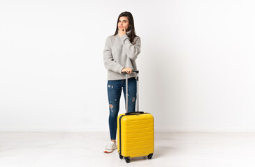 A full length body of a traveler woman with a suitcase over isolated white wall thinking an idea