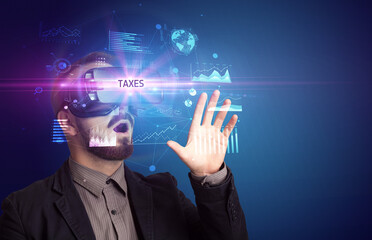 Businessman looking through Virtual Reality glasses with TAXES inscription, new business concept