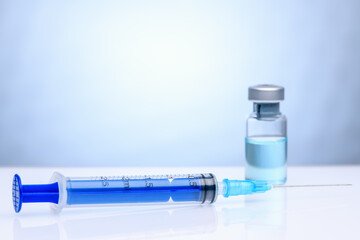 The coronavirus vaccine and syringe injection. Vial with vaccine against coronavirus on a light blue background. The concept of protection against coronavirus infection, COVID-19.