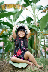 Cute Little girl covering head with book after study at the garden