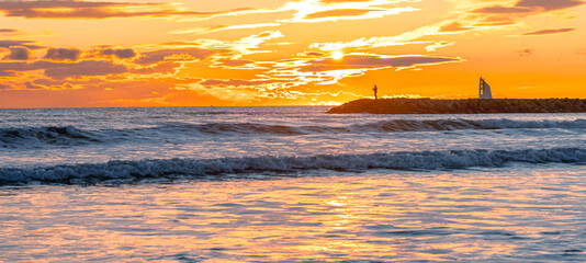 Panorama d'un coucher de soleil sur une digue avec vue sur le phare de La Grande Motte, sud de la France près de la Camargue.  © ODIN Daniel