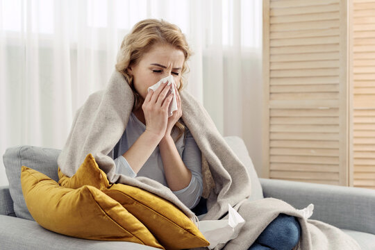 Ill woman with runny nose sneezes into a napkin
