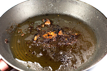 Burnt pan with oil. Fat leftovers close up. Unhealthy food. Damaged kitchenware.