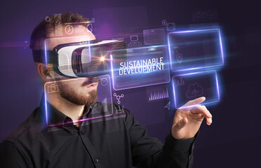 Businessman looking through Virtual Reality glasses with SUSTAINABLE DEVELOPMENT inscription, new technology concept