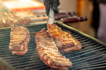 Ribs are turned over on the grill. BBQ ribs. Street food.