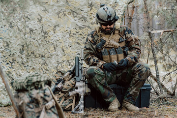 Obraz premium Squad Leader Discusses Military Operation Details with Soldiers, Commander Gives Orders. Fully Equipped and Armed Soldiers Ready for Mission in a Dense Forest.