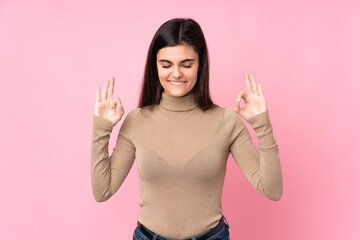 Young woman over isolated pink background in zen pose