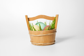 Fototapeta premium Easter composition, eggs in a basket with green grass on a white background. Eggs are painted with natural dyes.