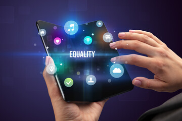 Businessman holding a foldable smartphone with EQUALITY inscription, social media concept