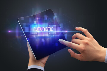 Businessman holding a foldable smartphone with FUTURISTIC inscription, new technology concept