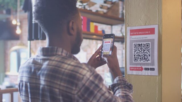 Man with mobile phone checking into venue scanning QR code during health pandemic - shot in slow motion