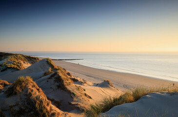 sea, beach and dunes at sunset