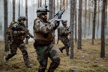 Fully Equipped Soldiers Wearing Camouflage Uniform Attacking Enemy, Rifles in Firing Position. Military Operation in Action, Squad Running in Formation Through Dense Forest at Midday.