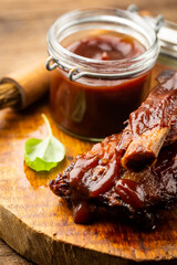 Delicious BBQ baby-back ribs with tangy sauce and a basting brush on wooden cutting board