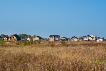 Cottage village. Autumn view of a modern cottage village in a dry yellow field.