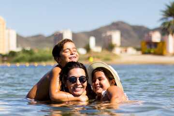 Fototapeta premium mother embracing her children in the sea