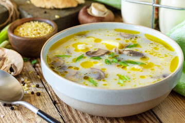 Mushroom cream soup with bulgur and cream on rustic table close-up.