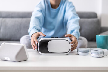 Hands of a Beautiful girl on the couch in her living room picking up a virtual reality glasses