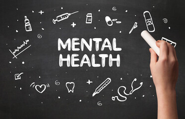 Hand drawing MENTAL HEALTH inscription with white chalk on blackboard, medical concept