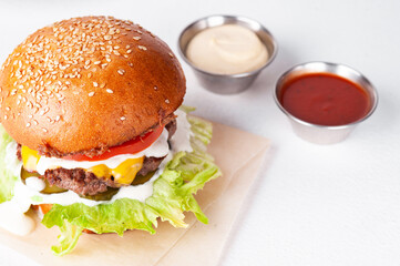 Closeup of big cheeseburger on white in restaurant