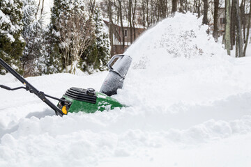Snow blower in action clearing a residential driveway after snow storm