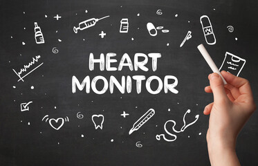 Hand drawing HEART MONITOR inscription with white chalk on blackboard, medical concept