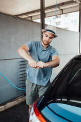 Fototapeta na wymiar Young handsome man with hat cleaning car with rag, car detailing (or valeting) concept.