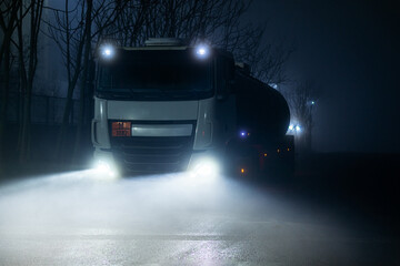 Tank truck with dangerous goods circulating at night on a foggy day.